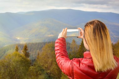 Güzel dağ manzarasının fotoğrafını çeken dişi turist.