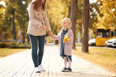 Küçük kız ve annesi birlikte parkta yürüyüş