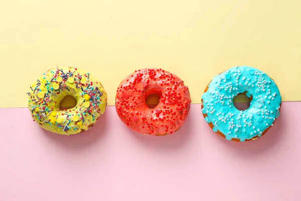 Sabrosas rosquillas con salpicaduras sobre fondo de color — Foto de Stock