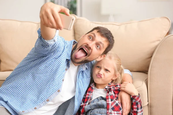 Aranyos kis lány és az apja vesz vicces selfie otthon — Stock Fotó