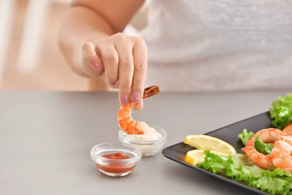 Jovem mulher comendo camarão à mesa — Fotografia de Stock