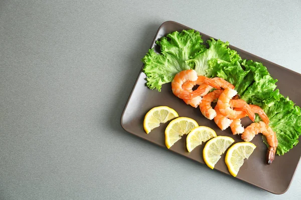 Тарілка зі смачними креветками, салатом і лимоном на столі — стокове фото
