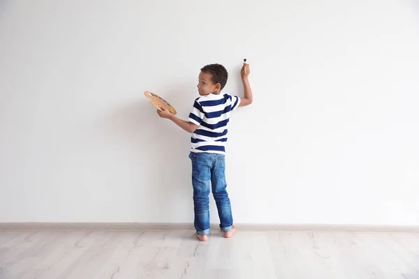 Menino afro-americano pintando na parede dentro de casa — Fotografia de Stock