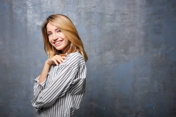 Femme souriante en chemisier rayé sur fond gris — Photo