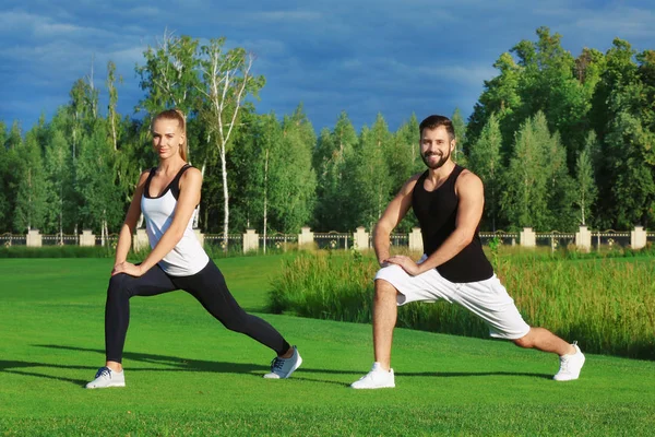 Joven pareja deportiva haciendo ejercicio en parque verde — Foto de Stock