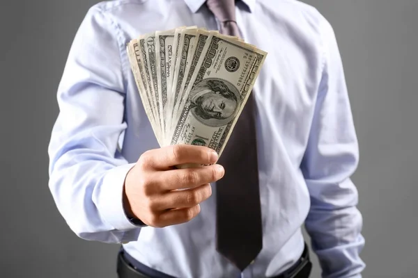 Homem de roupas formais segurando dinheiro em fundo cinza — Fotografia de Stock