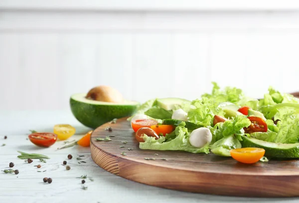 Tablero de madera con deliciosa ensalada de verduras en la mesa, primer plano —  Fotos de Stock