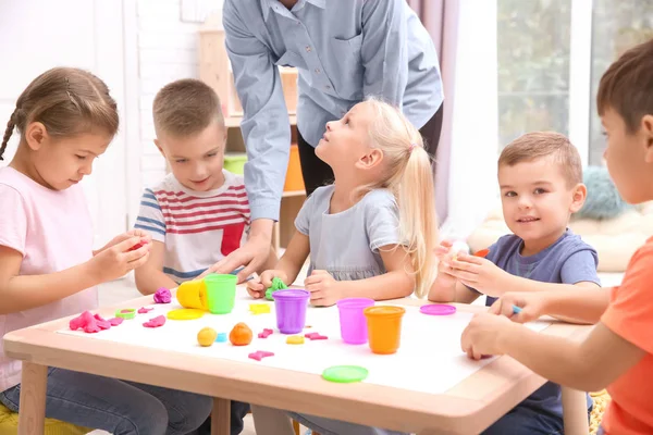 Crianças pequenas envolvidas em modelagem de massa de brincar na creche — Fotografia de Stock