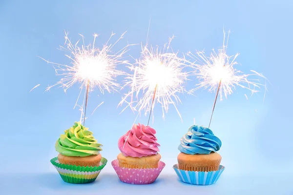 stock image Delicious cupcakes with sparklers on light background