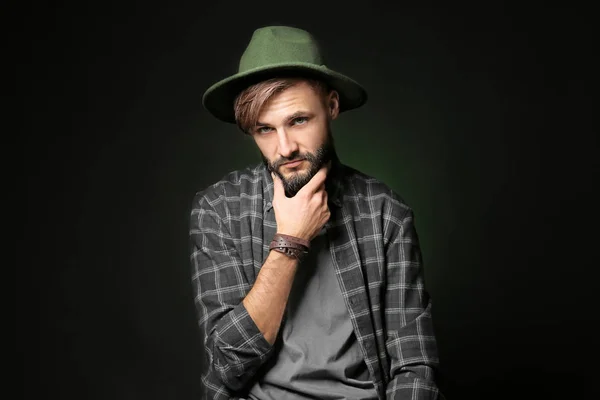 Thoughtful young hipster man on dark background — Stock Photo, Image