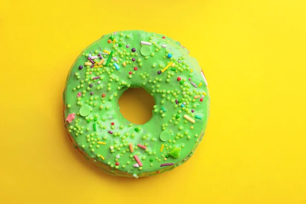 Вкусный зеленый пончик на желтом фоне, вид сверху — стоковое фото