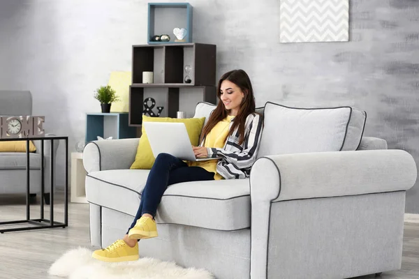 Молода жінка з ноутбуком на дивані вдома — стокове фото