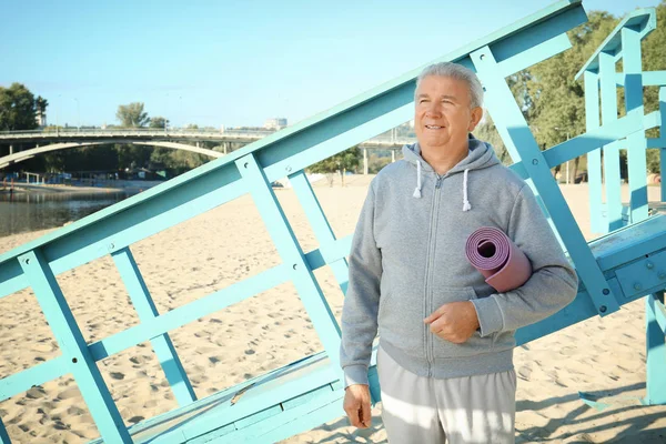 Homme mûr avec tapis debout sur la plage — Photo