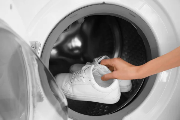 Mulher colocando tênis brancos na máquina de lavar roupa, close-up — Fotografia de Stock