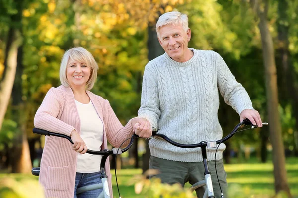 Carina coppia anziana con biciclette nel parco autunnale — Foto Stock