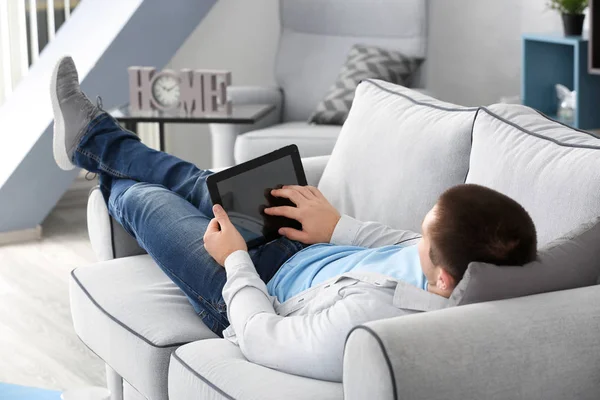 Joven con la tableta en el sofá en casa — Foto de Stock