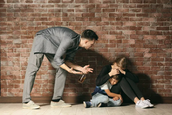 Bêbado homem ameaçando sua esposa e filho contra tijolo parede — Fotografia de Stock