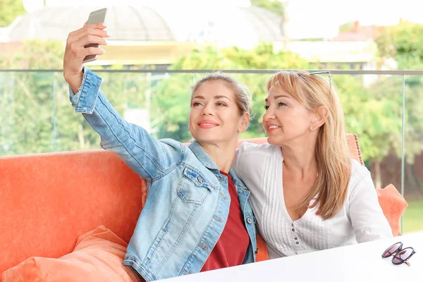 Zralá žena a její dcera, přičemž selfie v kavárně — Stock fotografie