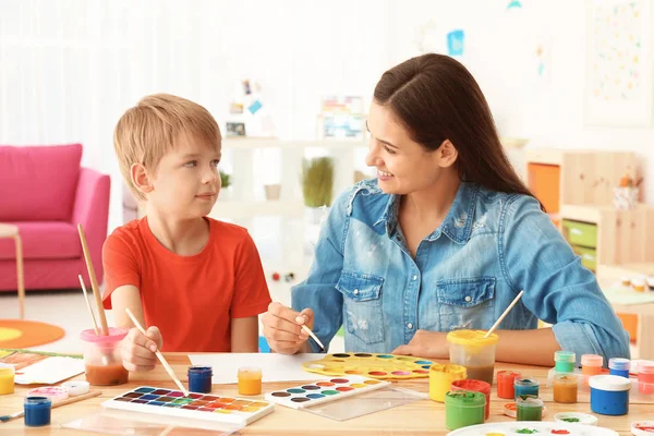 Garçon mignon avec la peinture de mère à la table dans la chambre — Photo