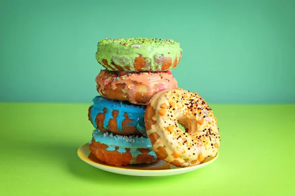 Plate with colorful donuts on green table — Stock Photo, Image