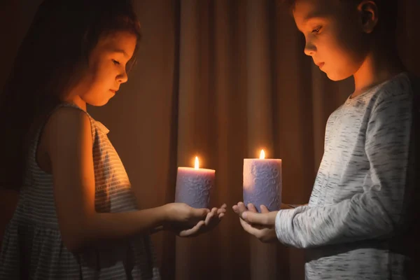 Malé děti drží hořící svíčky v temnotě — Stock fotografie