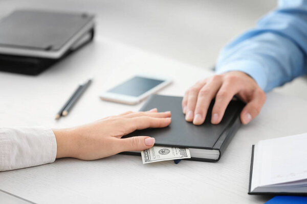 Женщина дает взятку бизнесмену в офисе, крупным планом
