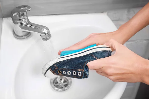 Kvinna tvätt sneaker med trasa i diskhon, närbild — Stockfoto