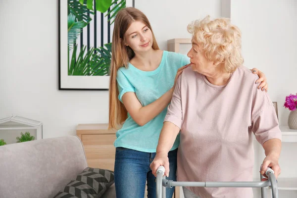 Mujer joven y su abuela anciana con marco para caminar en casa — Foto de Stock