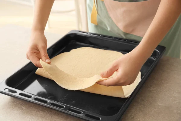 Woman putting puff pastry on baking tray — Stock Photo, Image