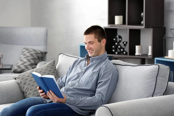 Νεαρός άνδρας ανάγνωση βιβλίο στον καναπέ στο σπίτι — Φωτογραφία Αρχείου