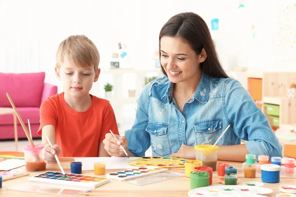 Lindo chico con madre pintura en la mesa en la habitación —  Fotos de Stock