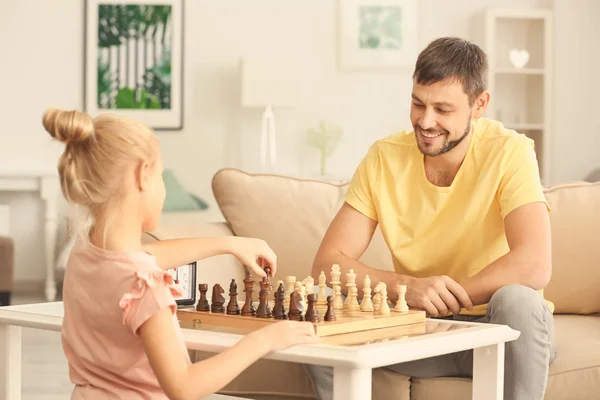 Χαριτωμένο κορίτσι παίζει σκάκι με τον πατέρα της στο σπίτι — Φωτογραφία Αρχείου