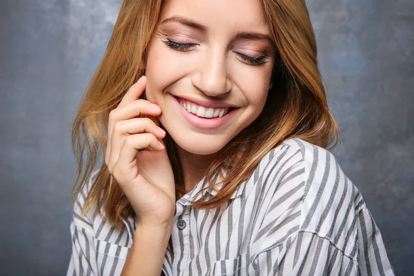 Usmívající se žena v pruhovaná halenka na šedém pozadí — Stock fotografie