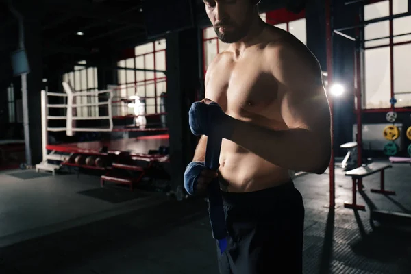 Boxer maschile che applica impacchi per le mani mentre si prepara per l'allenamento in palestra — Foto Stock