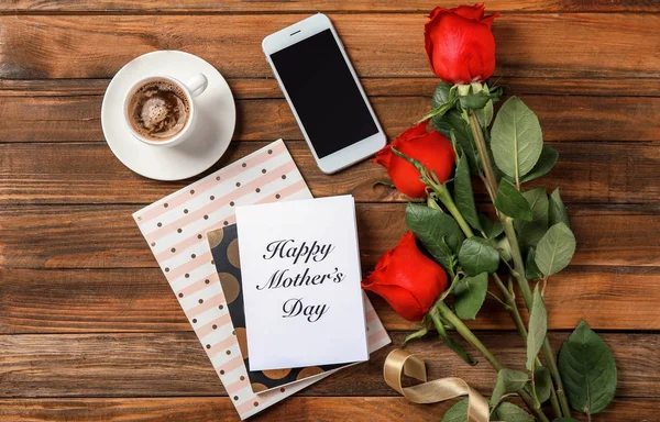 Composición del Día de la Madre con tarjeta de felicitación, rosas rojas y teléfono celular sobre fondo de madera — Foto de Stock