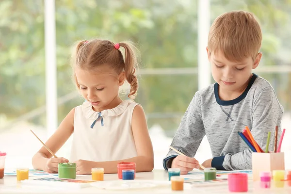 Schattige kinderen schilderij van foto's aan tafel binnenshuis — Stockfoto