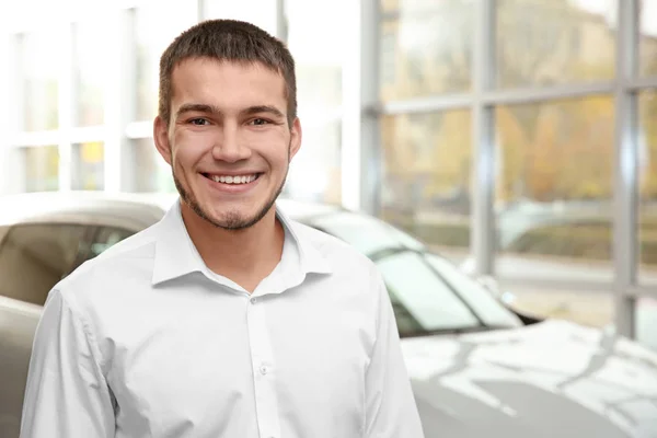 Handsome car salesman in dealership centre — Stock Photo, Image