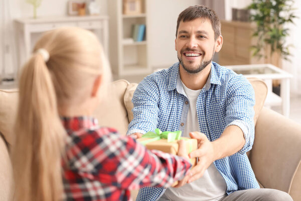 Cute little girl greeting her dad with Father's Day at home