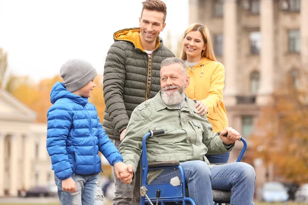 Yaşlı adam açık havada sonbahar günü ailesiyle birlikte tekerlekli sandalyede — Stok fotoğraf