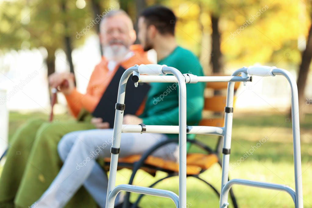 Young caregiver sitting with senior man 