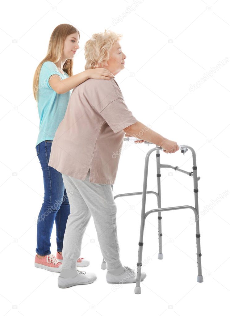 Young woman and her elderly grandmother with walking frame on white background