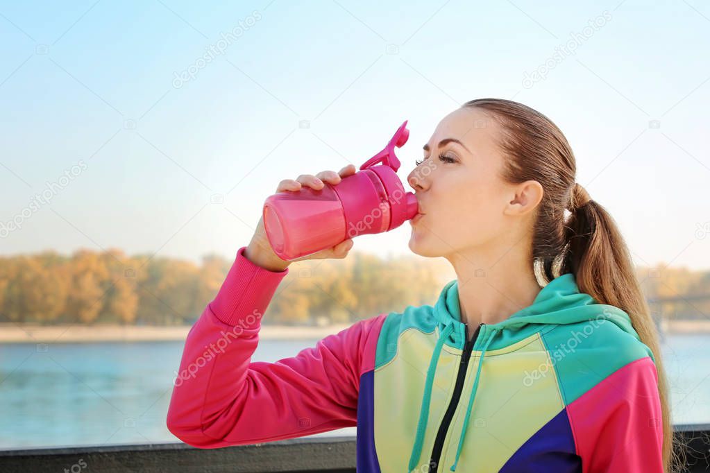 Young woman drinking protein shake outdoors