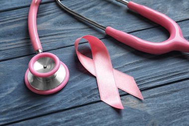 Pembe kurdele ve stetoskop ahşap arka plan üzerinde. Meme Kanseri Bilinçlendirme kavramı