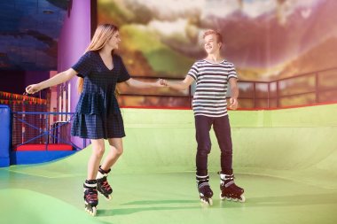 Cute teenage couple at roller skating rink clipart