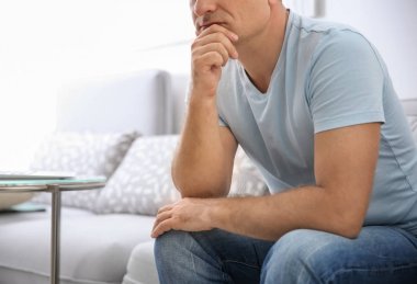 Evde koltukta oturan düşünceli olgun adam