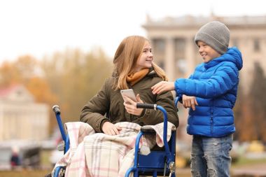 Tekerlekli sandalye ile kardeşi sonbahar günü açık havada genç kız