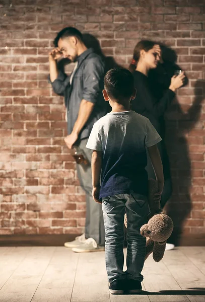 Little boy holding teddy bear while his parents having quarrel on background — Stock Photo, Image