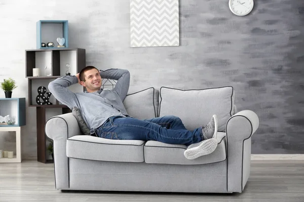 Молодой человек отдыхает дома на диване — стоковое фото