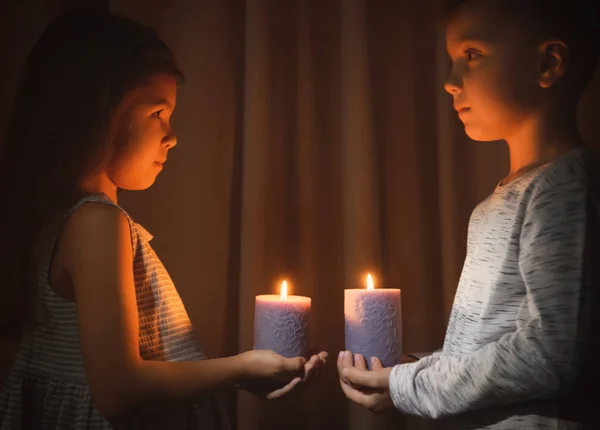 Little children holding burning candles in darkness — Stock Photo, Image