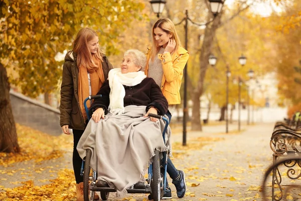 Açık havada sonbahar günü ailesiyle birlikte tekerlekli sandalyede yaşlı kadın — Stok fotoğraf